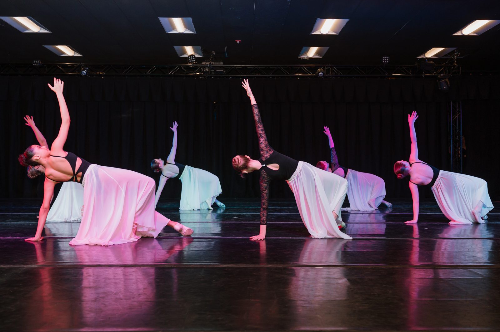 Dancers performing on stage under colored lighting