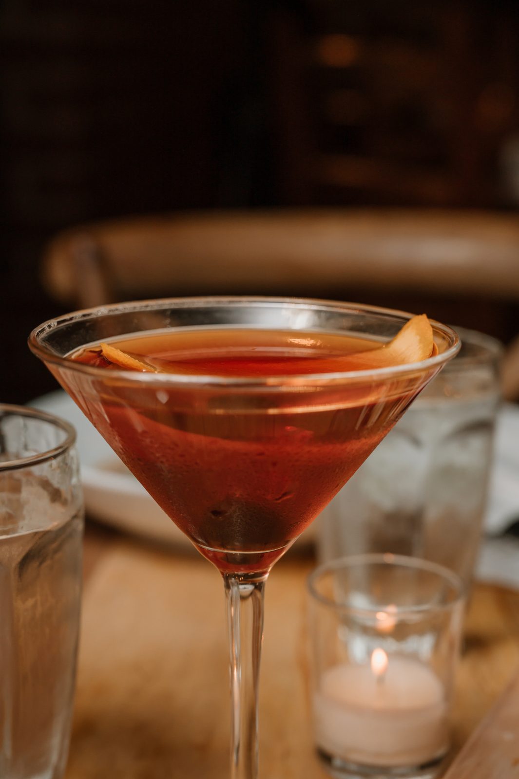 Craft cocktail garnished with orange peel on a bar top